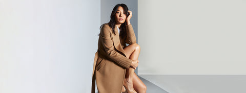 Sentaler Long Notched Collar Wrap Coat crafted in Baby Alpaca wool and in Dark Camel. Seen from side open on female model seen sitting.
