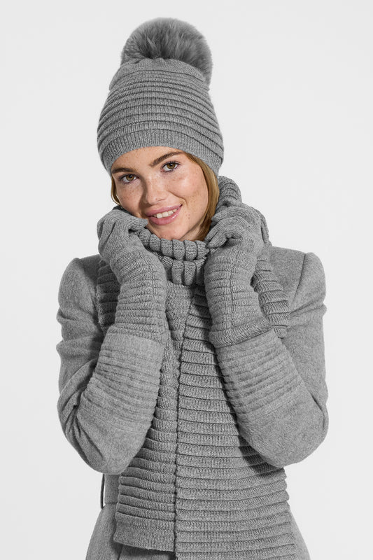 Sentaler Adult Ribbed Hat With Oversized Fur Pompon, Ribbed Scarf and Ribbed Gloves featured in Baby Alpaca and available in Grey. Seen from front above the waist on model.