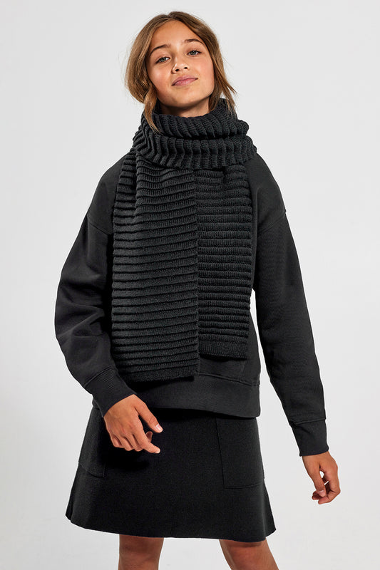 Sentaler Kids (6-14 Years) Ribbed Scarf featured in Baby Alpaca and available in Black. Seen from front above the knees on model.